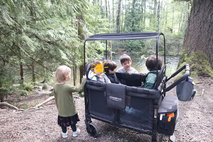 Children in a stroller wagon outdoors near a river