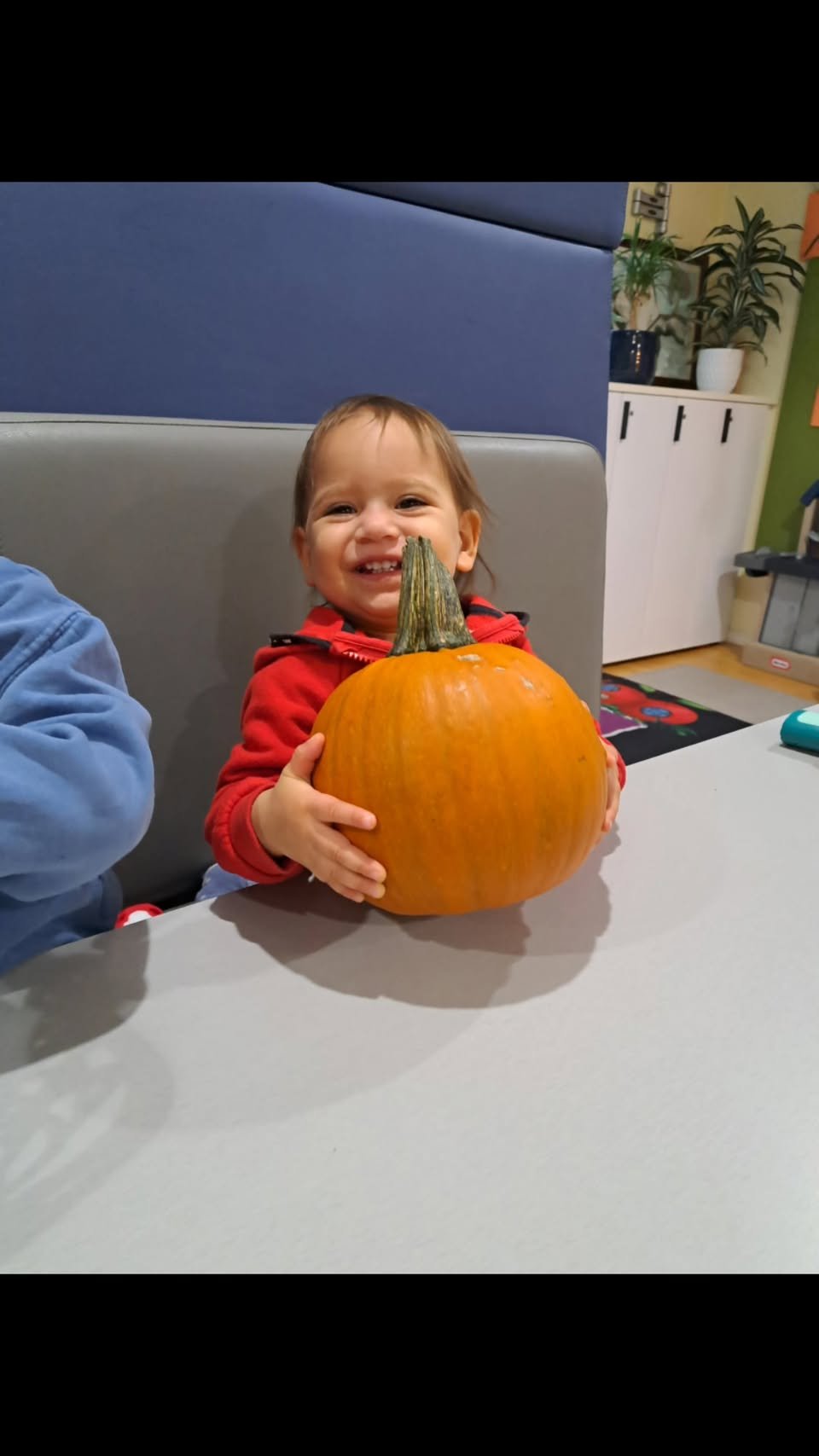 Child happily holding a large pumpkin