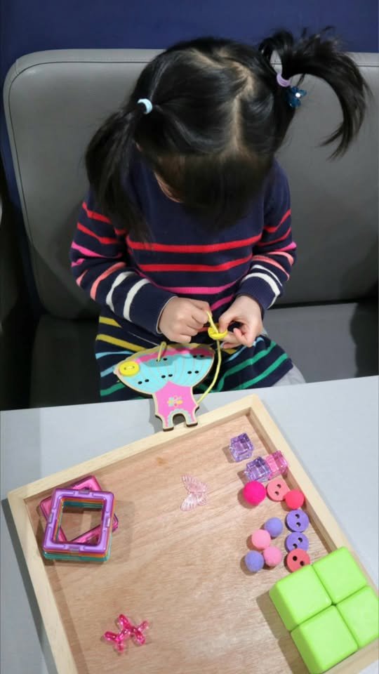 Child doing lacing activity and organizing small pieces
