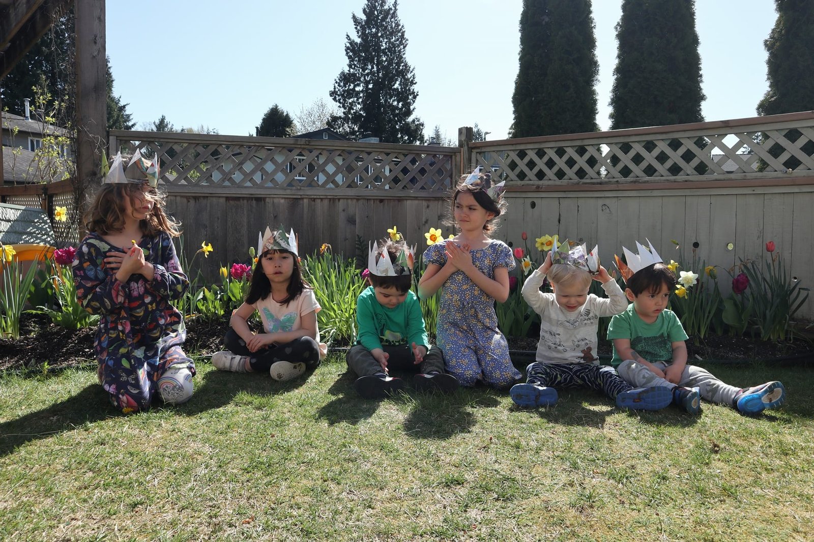 Children sitting outside with paper crowns