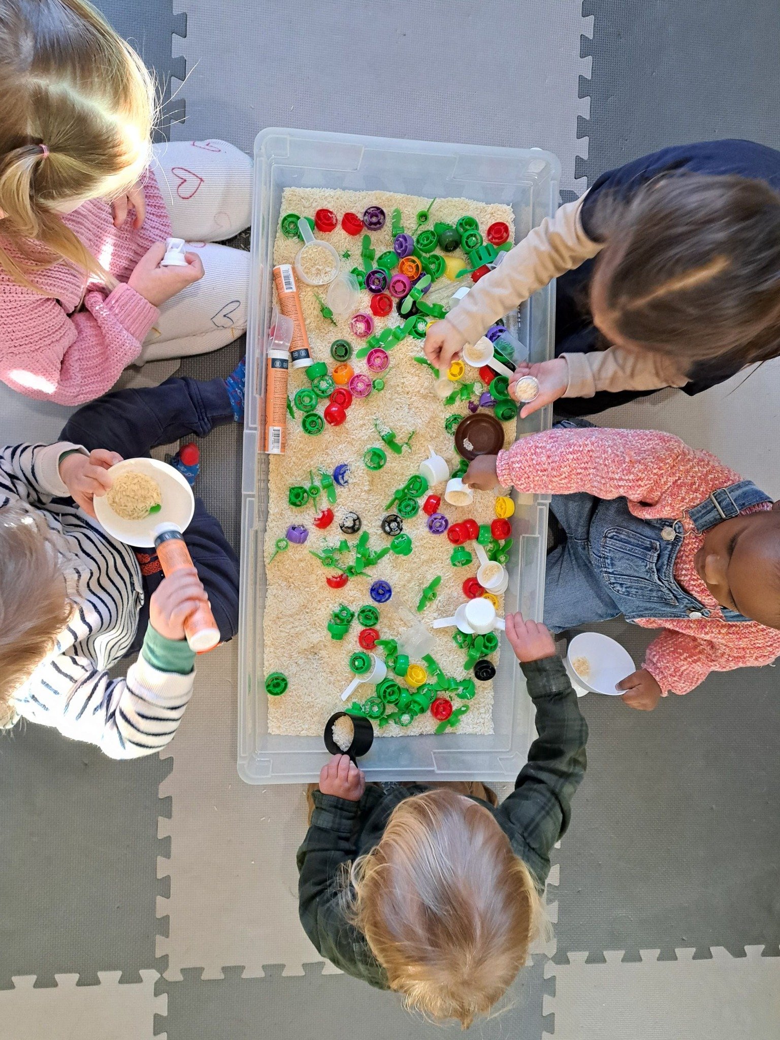 Sensory bin play with colored lids and rice
