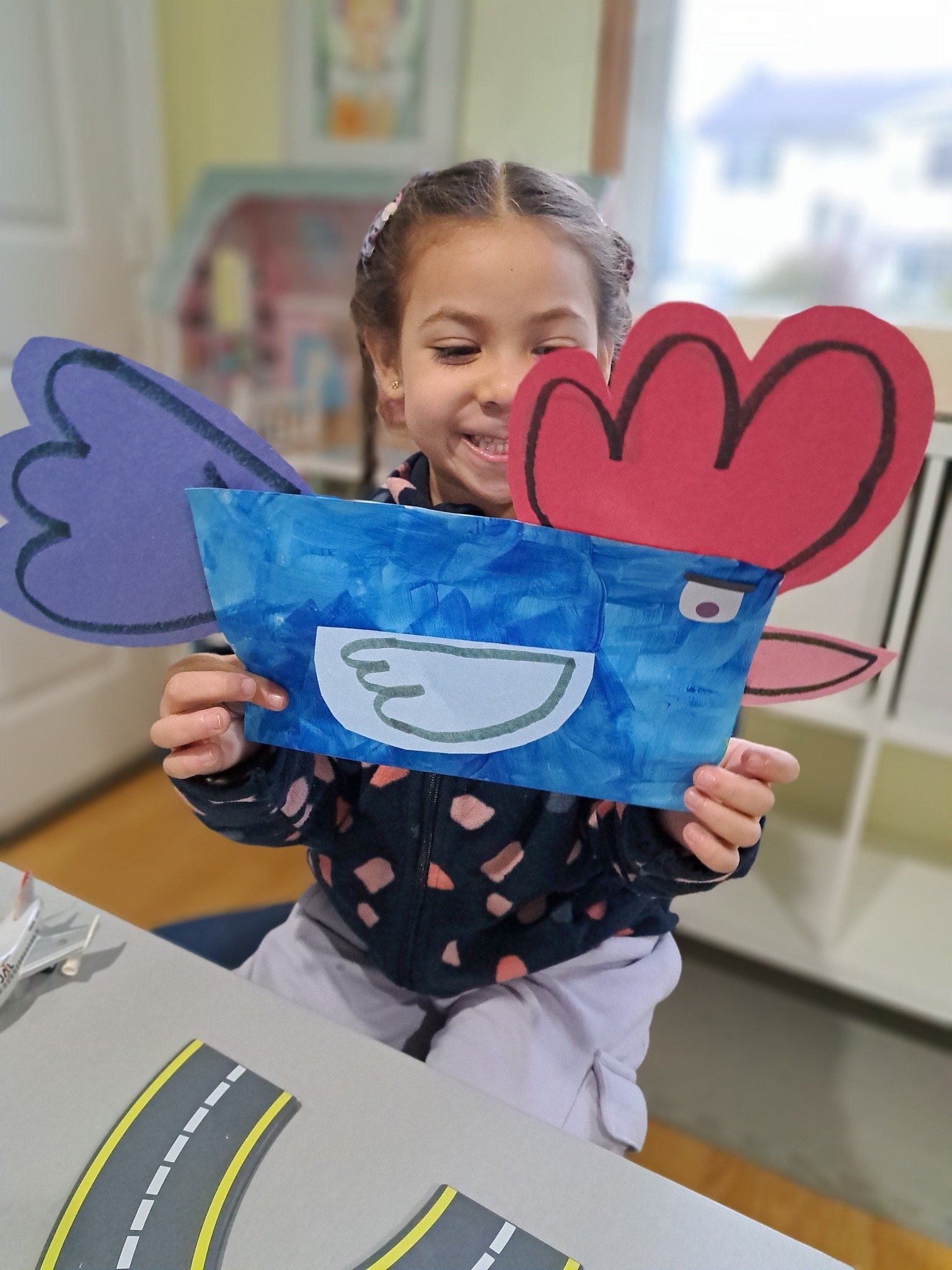 Child holding up a homemade rooster craft