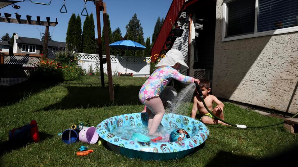 Kids playing in a pool with a water hose